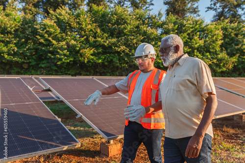 técnico de instalação de painéis fotovoltaicos vestindo equipamentos de segurança explicando sobre a energia solar para o fazendeiro Brasileiro photo