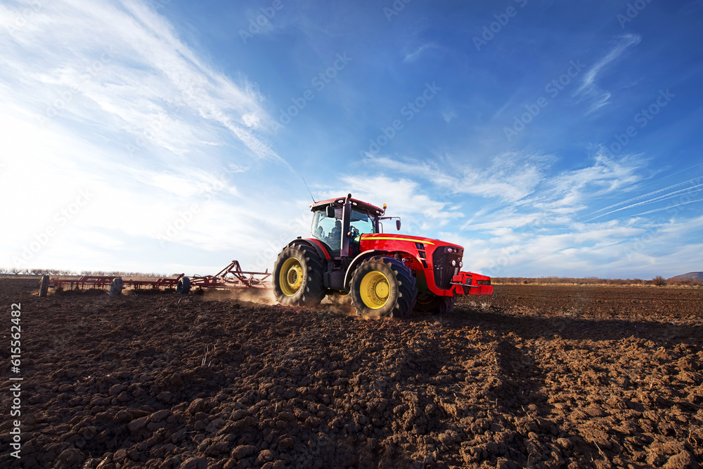 Fototapeta premium Tractor cultivating field at spring.