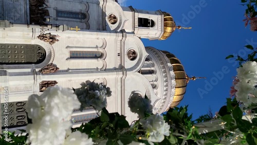 View of Cathedral of Christ the Saviour in Moscow, Russia through frame of white blooming flowers. Clear blue sky. Slow motion vertical video. Easter holiday theme.	