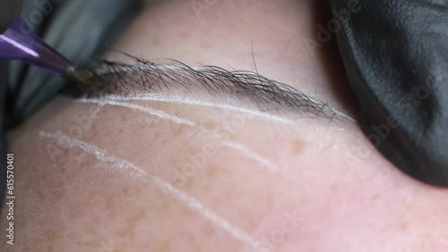 Close-up of microblading process: art of eyebrow tattooing. With gloved hands, skilled practitioner wields aspecialized needle, embedding pigment into skin. eyebrows are meticulously tinted using photo