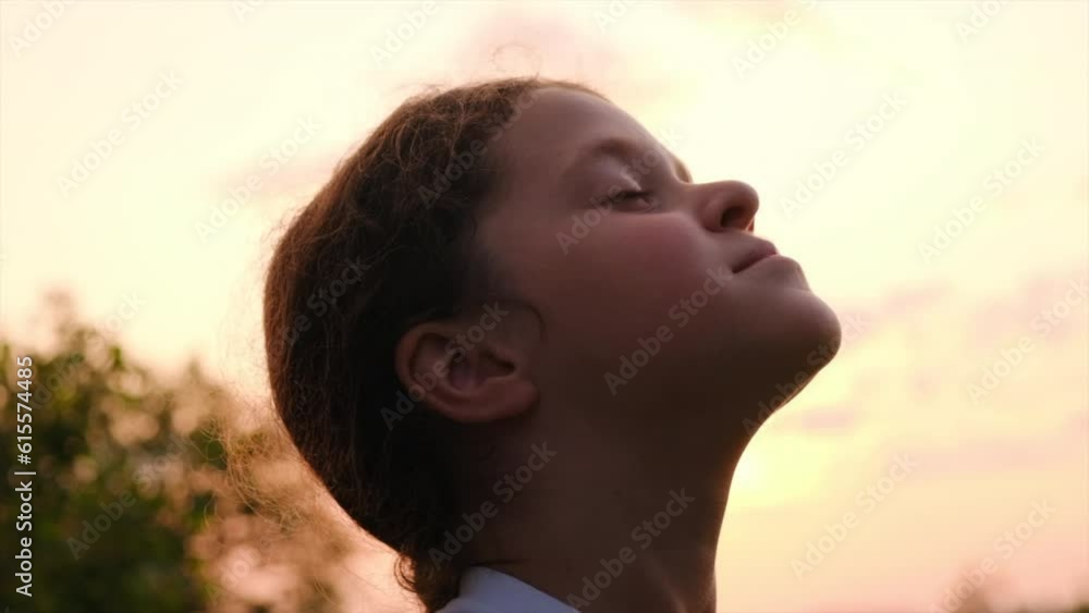 Close up portrait of charming little girl opens eyes and enjoy calm nature at warm sunset in summer. Dreamy peaceful relaxed smiling kid breathing fresh air on background mountains and amazing sky Close up portrait of charming little girl opens eyes and enjoy calm nature at warm sunset in summer. Dreamy peaceful relaxed smiling kid breathing fresh air on background mountains and amazing sky