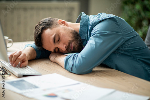 Fotografie Portrait Of Tired Young Office Employee Sleeping At Workplace