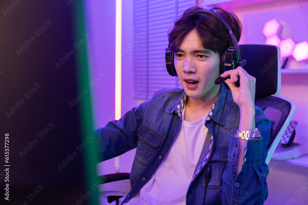 Asian Gamer Playing in Online Video Game While Talking to His Teammate with Headphone Asian Gamer Playing in Online Video Game While Talking to His Teammate with Headphone