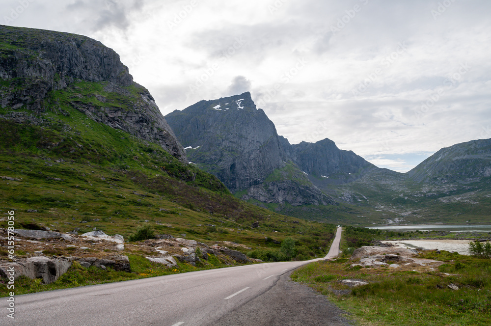 Road on the coast along the high mountains in the bay of the fjord. Lofoten, Norway.