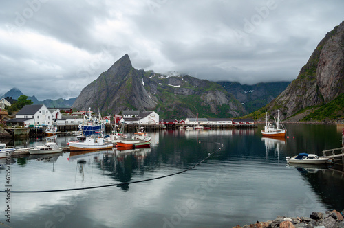 A bay between mountains with moored fishing boats and wooden houses in the background - Svolvaer, Norway