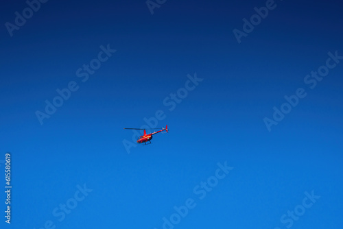 Red helicopter fly in clear blue sky