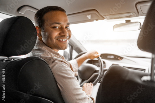 Smiling indian guy driver sitting inside brand new car © Prostock-studio