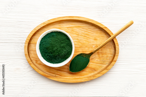 Spirulina or seaweed powder in bowl and in spoon, top view. Super food concept