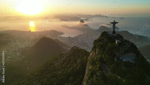 Rio de Janeiro, Brazil - June 10, 2023: Aerial view of Christ the Redeemer statue on top of the Corcovado Mountain with the Sugarloaf Mountain in the horizon on sunrise.