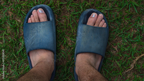 pies de adulto joven con sandalias y uñas pintadas en el jardin