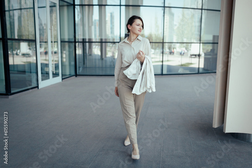 Successful caucasian business woman in a business suit comes out of a modern office building.