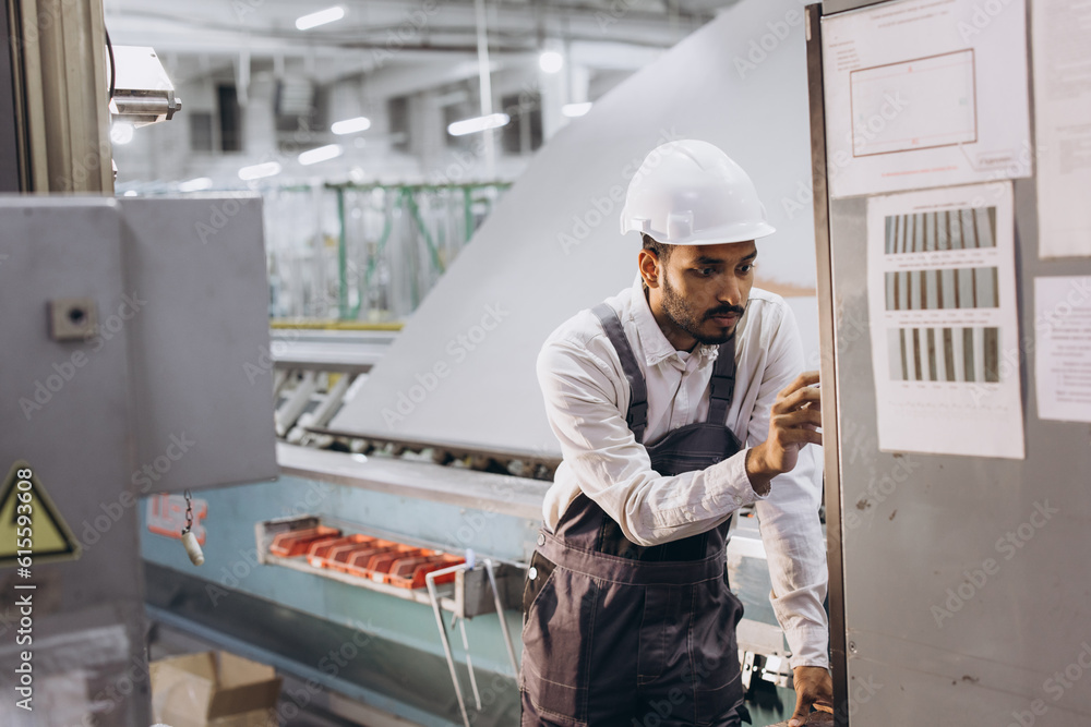 Operator of machine. Industrial worker indoors in factory. Young technician in white hard hat. Operator of machine. Industrial worker indoors in factory. Young technician in white hard hat.