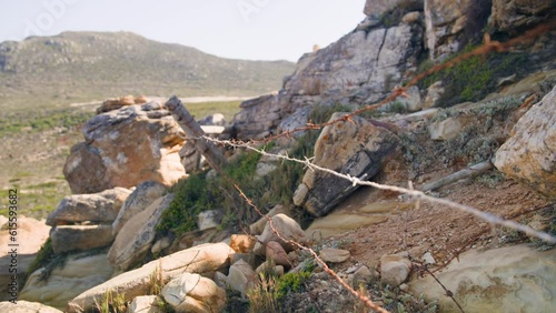 Barbed wire fence outdoors with mountains in background at sunny day at cape point national park