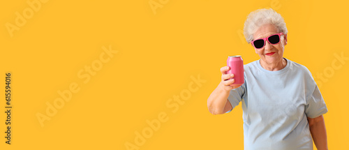 Stylish senior woman in sunglasses ad with soda drink on yellow background with space for text