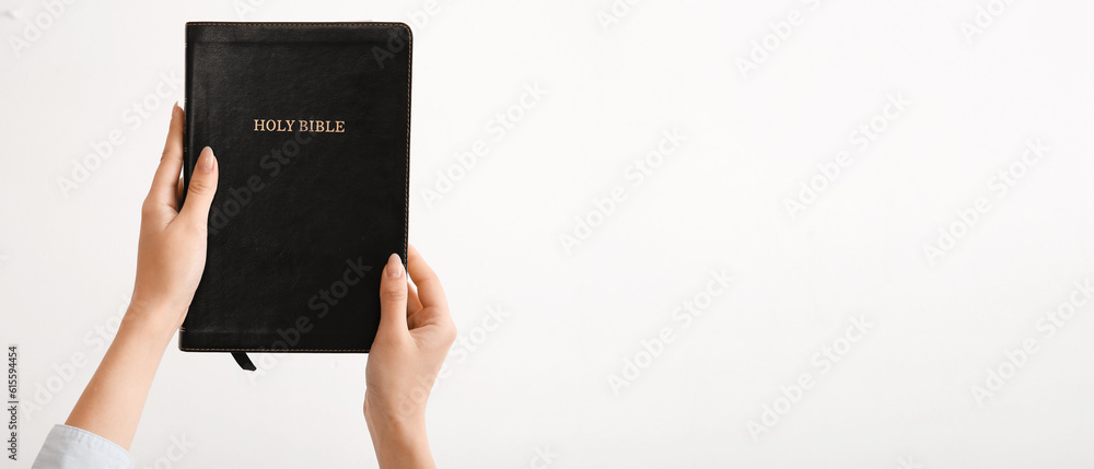 Female hands holding Holy Bible on light background with space for text Female hands holding Holy Bible on light background with space for text