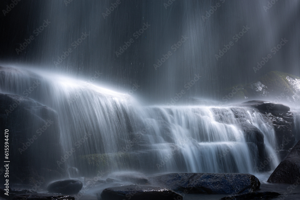 Obraz premium Fast moving waterfall cascade flowing down wet rocks