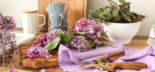Billede på lærred Beautiful lilac twigs on wooden kitchen table