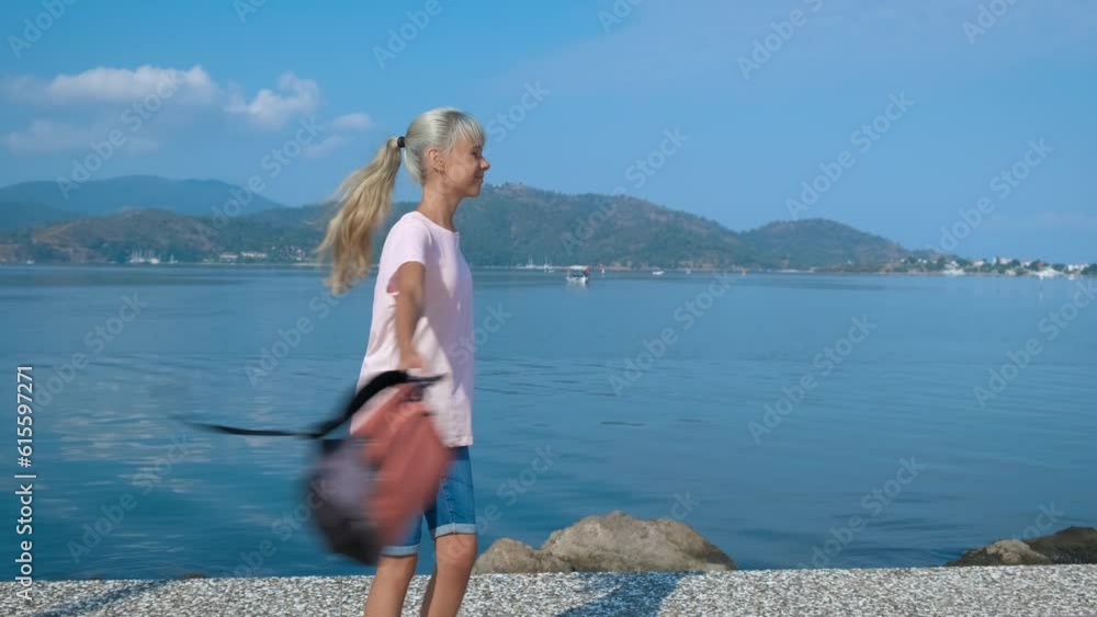 Happy tourist. A young teenage girl is spinning with a backpack on the background of the blue sea. Happy tourist. A young teenage girl is spinning with a backpack on the background of the blue sea.