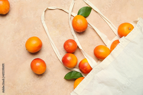 Eco bag with scattered tasty blood orange fruits on beige background