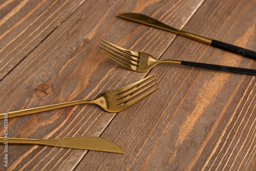 Golden forks and knives on wooden background