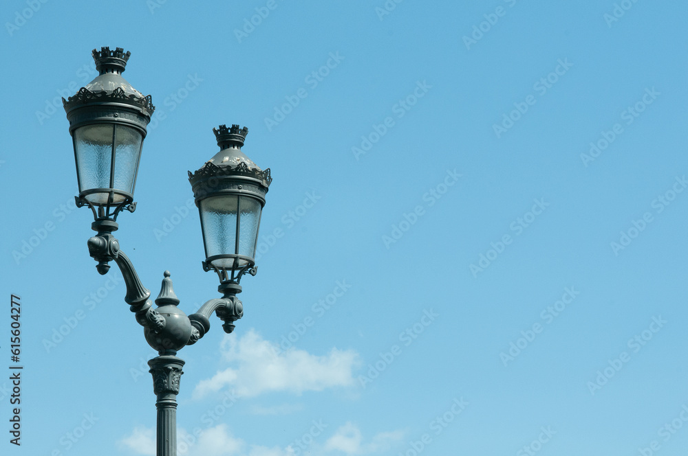 Front view, medium distance of, two historic, handmade, metal, street lamps, against blue sky,  in Reim, France