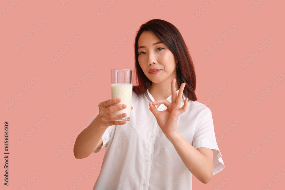 Beautiful Asian woman with glass of milk showing OK on pink background Beautiful Asian woman with glass of milk showing OK on pink background