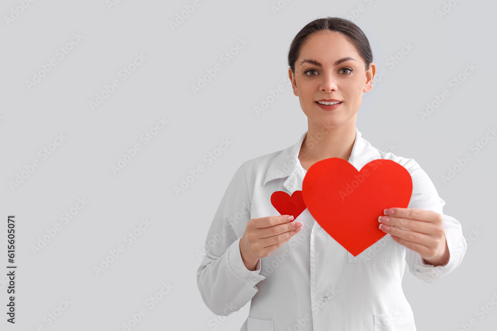 Female doctor with paper hearts on light background. Blood donation concept Female doctor with paper hearts on light background. Blood donation concept