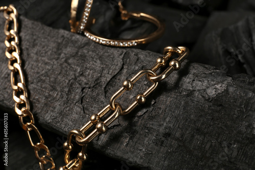 Beautiful chain bracelets and earrings on black charcoal, closeup