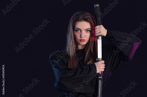 Beautiful young woman with katana on dark background © Pixel-Shot