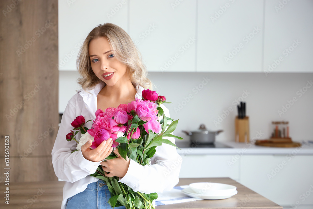 Young woman with peony flowers in kitchen