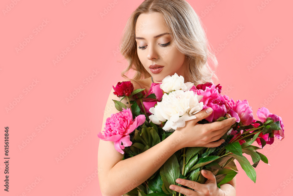 Young woman with beautiful peony flowers on pink background