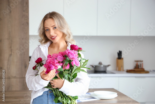Young woman with peony flowers in kitchen