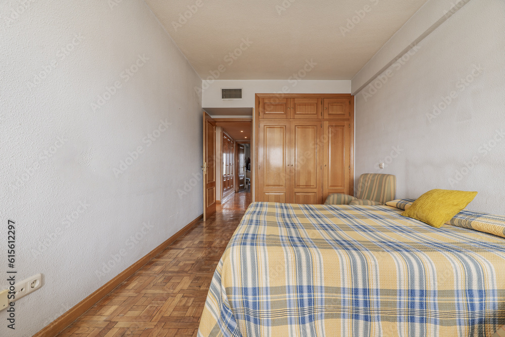 Naklejka premium Bedroom with two double beds, plaid bedspread, and built-in oak