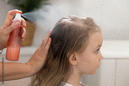 Women's hands apply a remedy for lice and nits on the head of a little girl. Getting rid of parasites and pests, childhood diseases.