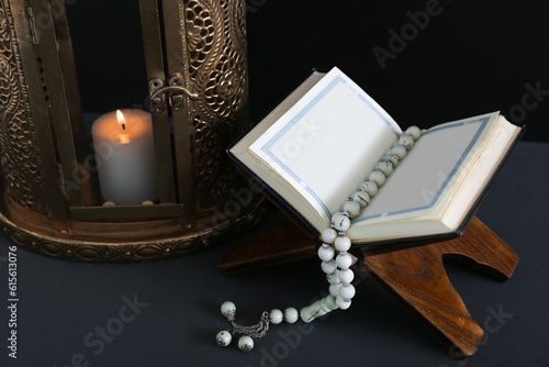 Fanous with burning candle, Koran and tasbih on dark background, closeup. Islamic New Year celebration photo