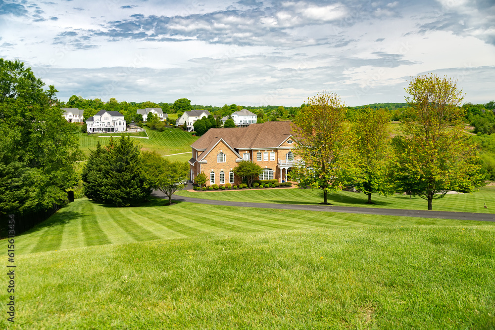 Fototapeta premium Large, beautiful, single-family brick country house. Large lawn and green trees.
