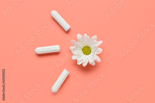 Composition with menstrual tampons and chamomile flower on coral background