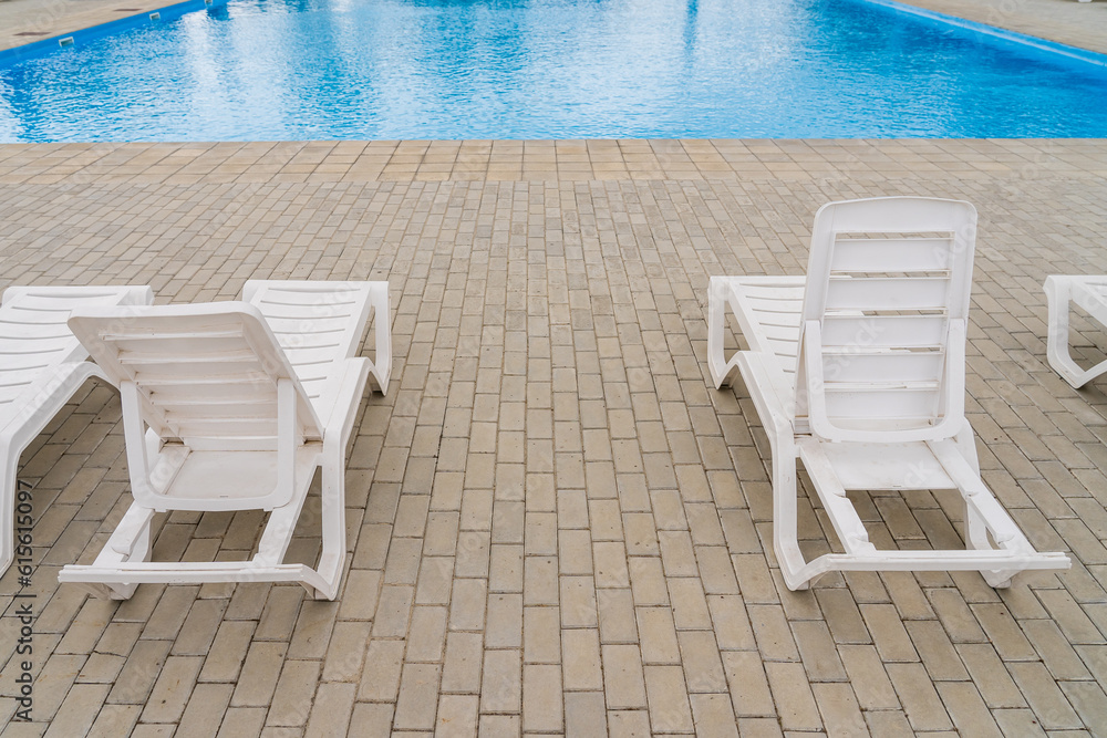 Fototapeta premium Empty sun loungers in the resort area by the pool. Background with copy space for text