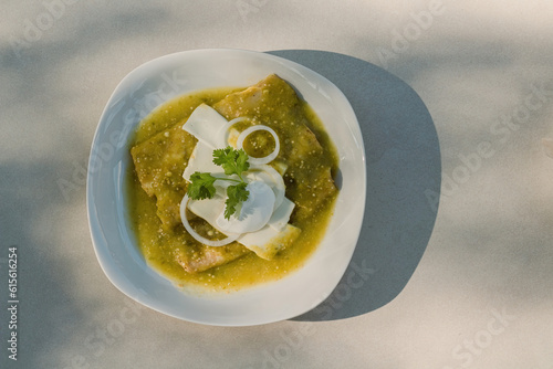 The Mexican enchiladas verdes, a staple food in Mexican cuisine, are served on a plate