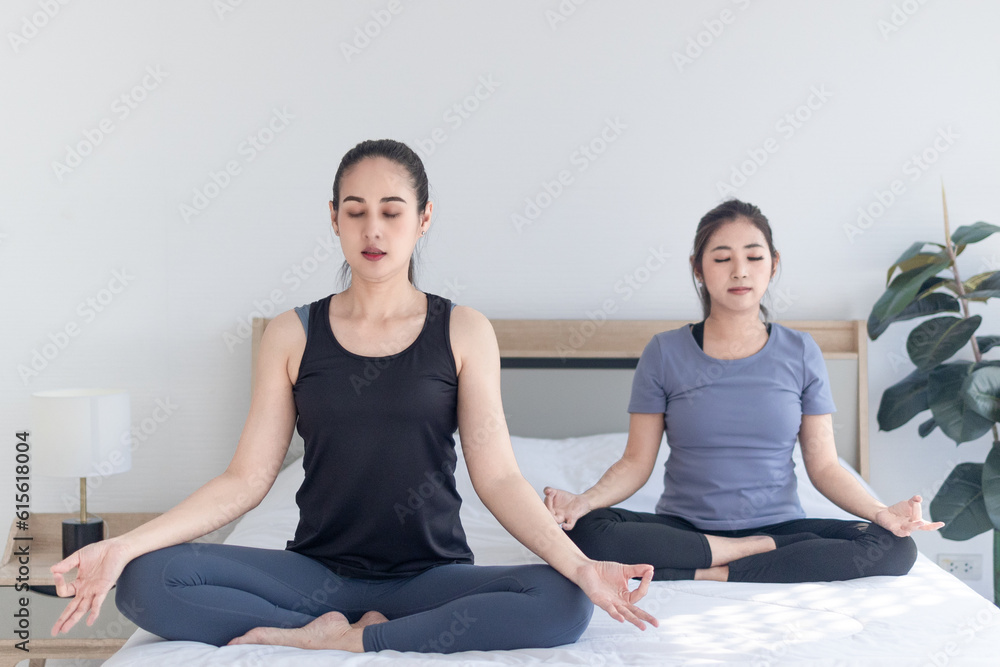 two women sitting doing yoga at home, mindful meditation exercise concept two women sitting doing yoga at home, mindful meditation exercise concept