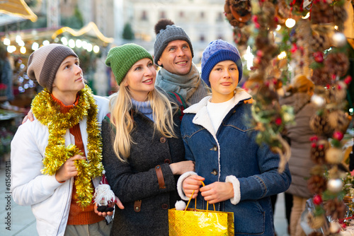 Portrait of positive family of four choosing christmas balls at Xmas street fair