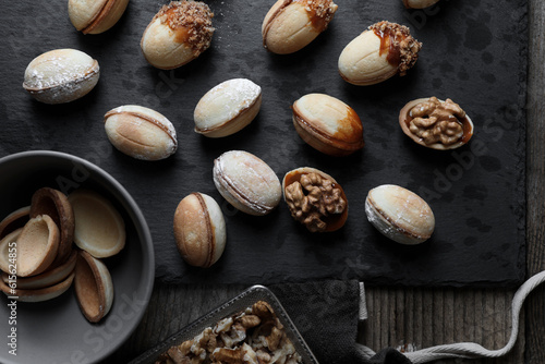 Freshly baked homemade walnut shaped cookies and nuts on wooden table, flat lay