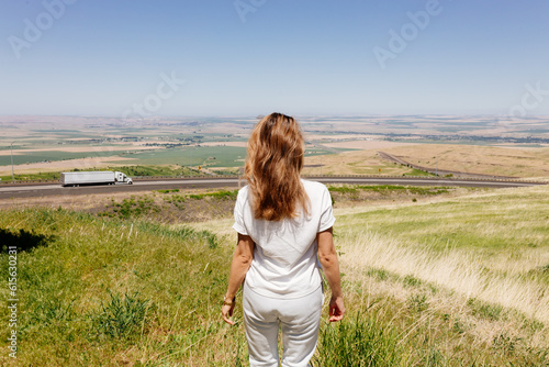 Beautiful summer landscape with meadows and a road from a bird's eye view. Nature in Oregon. A girl in sportswear with red hair walks in a summer meadow, rests in nature, admires nature