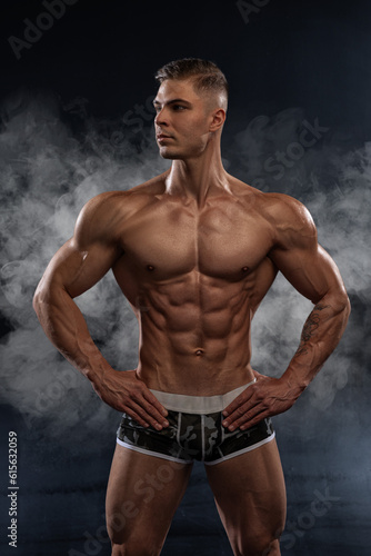 Bodybuilder showing off his perfect low fat body without clothes in studio