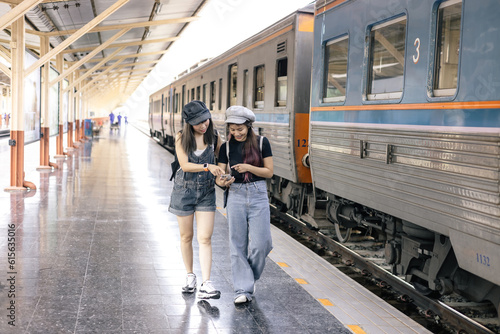 Two young woman traveler tourist booking train queue by smartphone . Active and travel lifestyle concept
