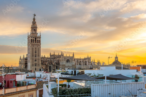 Sunset view from a rooftop overlooking the Andalusian city of Seville, Spain, with the Giralda Tower and the great Seville Cathedral in view over the skyline.