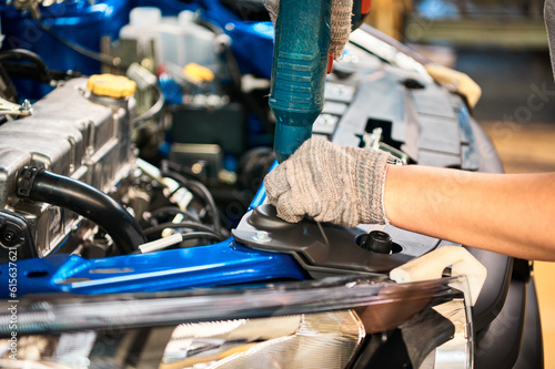Worker prepares to screw car body parts on workshop conveyor