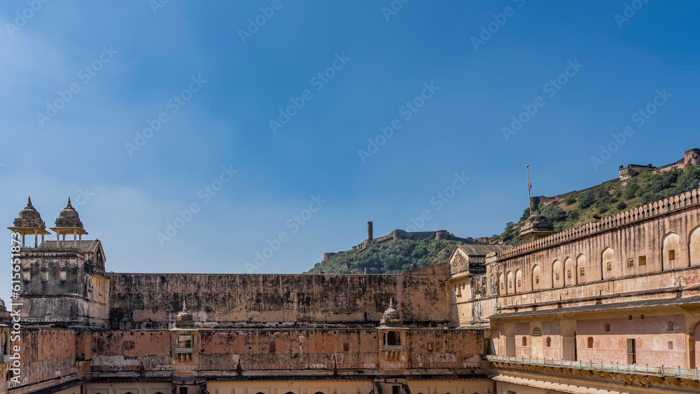 Ancient Amber Fort. Weathered walls, towers with domes against the blue sky. The fortress wall is visible on the ridge of the mountain. Jaipur. India.