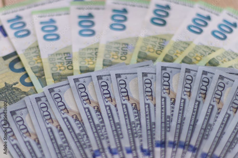 One hundred dollar bills next to one hundred euro bills., Currency exchange rate concept. One hundred dollar bills next to one hundred euro bills., Currency exchange rate concept.