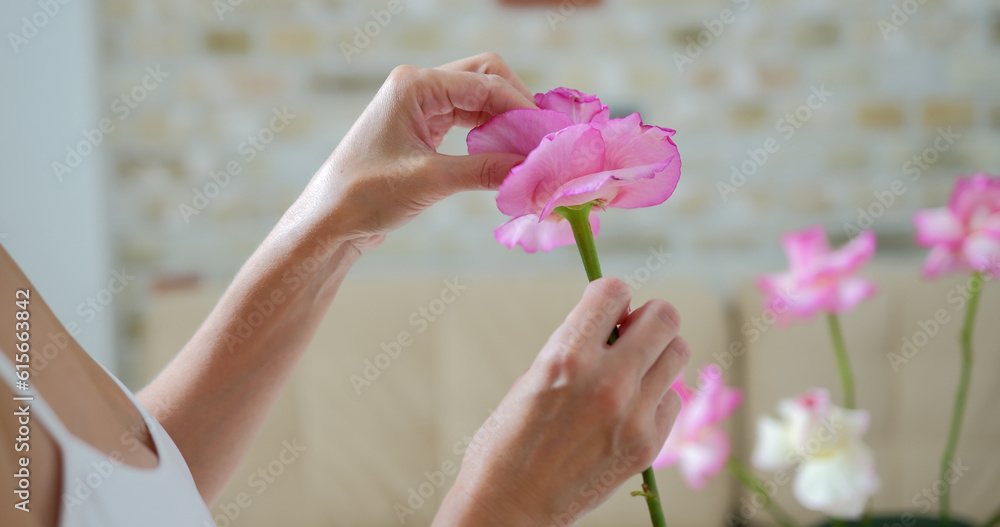Young woman florist in floral shop preparing bunch from roses